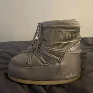 guldiga Moon Boots med snörning - Säljer ett par beige/guldiga Moon Boots med vanlig rund form och tjock platt sula. De har snörning runt hela skon och är tillverkade i syntetmaterial med mjuk och varm insida. Perfekt för vintern och snöiga dagar, eller bara för dem e snygga :) jag har 38/39 och de passar mig perfekt så tror de är 37-40 ish