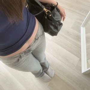 Lågmidjade grå jeans  - Säljer ett par grå jeans med låg midja och klassisk bootcut fit. Jeansen har fem fickor, bälteshällor och snygga detaljer vid bakfickorna. 