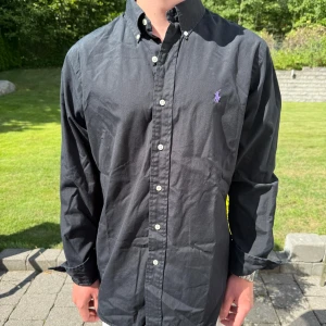 Svart Ralph Lauren Skjorta - Svart Ralph lauren skjorta || Storlek M (Custom Fit) || Skjortan är i bra skick, däremot något fläckig  || mitt pris 399kr || Modellen på bilden är 170cm och väger 62kg || tveka inte på att höra av dig vid frågor eller funderingar 