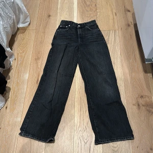 Svarta wide jeans från Gina Tricot - Snygga grå/svarta jeans från Gina Tricot i modellen 'the Good Project'. De har en bred, rak passform med hög midja och klassiska fem fickor. 