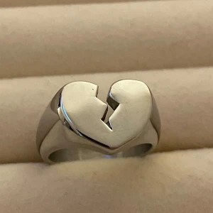 Silverring med brustet hjärta - Cool och chunky silverring med ett brustet hjärta som motiv. Ringen har en blank finish och är formad i ett stilrent, modernt snitt. Perfekt för dig som gillar statement-smycken med känsla och attityd.