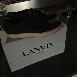 Marinblå sneakers från Lanvin Paris - Snygga marinblå sneakers från Lanvin Paris med lite sliten sula. Skorna har snörning och en stilren design med en mix av mocka och skinn på ovandelen. Kommer med originalkartong och dustbag. Går självklart att putsa till dem! Priset går att diskutera!