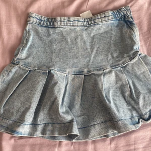 Ljusblå jeanskjol med volang från H&M - Supersöt ljusblå jeanskjol från H&M med volangkant nedtill. Kjolen har en klassisk jeanslook, dragkedja och knapp i sidan. Perfekt för dig som gillar en chill och trendig stil. Passar dig som vill ha en kort kjol med lite extra volym🤏❤️ pratar gärna om pris!!!