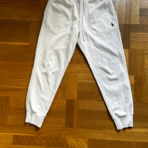 Vita mjukisbyxor Polo Ralph Lauren - Snygga vita mjukisbyxor från Polo Ralph Lauren med klassisk broderad logga på benet. Byxorna har dragsko i midjan, stora fickor framtill och ribbade muddar vid bensluten. Perfekta för chill eller streetwear. Tillverkade i mjuk bomull.