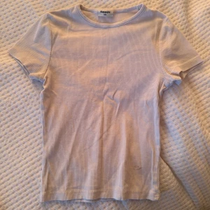 Ljusribbad t-shirt från Kappahl - Snygg ljus t-shirt från Kappahl i ribbad bomull. Modellen är klassisk med rund hals och korta ärmar, perfekt för en chill look. T-shirten har en slim passform och känns mjuk mot huden. Enkel att matcha med jeans eller shorts. En liten fläck som kan ses i sista bilden men som går lätt bort