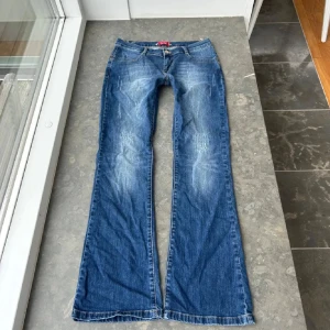 Blå bootcut jeans med slitningar - Snygga blå jeans med bootcut-modell och slitna detaljer framtill. Midjemått: 38 innebenslängd:78 Midjehöjd: 19cm 💘