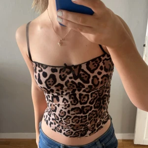 Leopardmönstrad croppad linnetopp - Säljer en croppad linnetopp med leopardmönster och tunna axelband från Zara. Toppen har en liten rosett framtill. Aldrig använt 