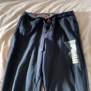 mörkblåa puma mjukisbyxor - stretchiga mörkblåa mjukisbyxor från puma. midjan har mått 60 och benen också. resorbanden har gått av lite men kan lätt sys på igen.