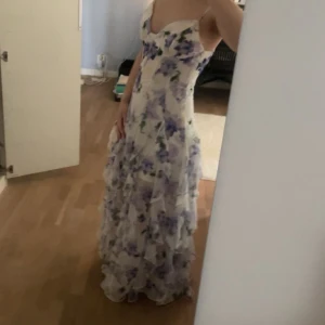 Lång blommig klänning med volangkjol - balklänning - Intressekoll på min fina balklänning/långklänning med blommigt mönster i lilablått och grönt på vit botten. Klänningen har smala axelband, v-ringning och flera volangdetaljer längs kjolen. Perfekt för en fin unik balklänning eller sommaren❤️köpt via Pinterest länk/hemsida!💗