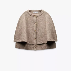 Beige stickad kofta från Zara - Säljer en beige stickad kofta från Zara med rund halsringning och knappar framtill. Koftan har en lös och cape-liknande passform med ribbade kanter. Perfekt för lager-på-lager under kyliga dagar. Den är aldrig använd och har prislappen kvar. Hör av dig vid några frågor❣️