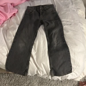Grå jeansbyxor från Chevy - Säljer ett par grå jeansbyxor från Chevy med klassisk femficksdesign och raka ben. Byxorna har normal passform och stängs med dragkedja och knapp. Perfekta för en avslappnad stil. 
