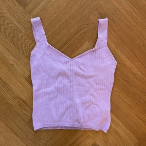 Ljuslila ribbad linnetopp från Design by Si - Supersöt ljuslila ribbad linnetopp från Design by Si. Toppen har breda axelband och en snygg v-ringning framtill. Perfekt att ha nu till sommaren!