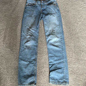 Blå raka jeansbyxor - Säljer ett par klassiska blå jeansbyxor med rak passform. Byxorna har fyra fickor, normal midja och med knapp framtill. Perfekta till vardags och lätta att matcha med olika stilar.
