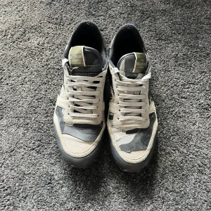 Valentino Rockrunner sneakers i grått och svart - Säljer ett par Valentino Rockrunner sneakers i grå, svart och beige camo. Skorna har klassisk snörning, rund tå och detaljer i mocka och skinn. Skick:6/10 hör av er vid intresse!//FR