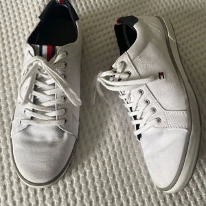 Vita sneakers från Tommy Hilfiger - Säljer dessa snygga vita sneakers från Tommy Hilfiger, skorna är använda en gång men inga stora defekter, nästan helt oanvända. Skorna är i storlek 41 och bara att höra av dig vid frågor.