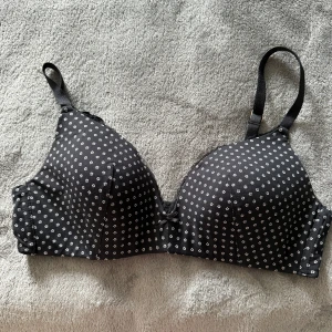 Body Essentials by Tchibo svart bh, storlek 80B - •Svart bh med ett mönster av små vita blommor.  •Bh:n har justerbara axelband och en traditionell hak-och-ögonsknäppning baktill. •Mycket bra skick. Knappt använd och tvättad. •Bh:n har vadderade kupor och knäppe bak.  •Söt liten rosett framtill ger en extra detalj.  •Perfekt för dig som gillar klassiska mönster med en twist. •Djurfritt och rökfritt hem.