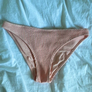 Ljusrosa bikiniunderdel från H&M - Säljer en ljusrosa bikiniunderdel från H&M i ribbat material. Klassisk modell med normal passform och stretchig känsla. Perfekt för strand eller poolhäng i sommar!