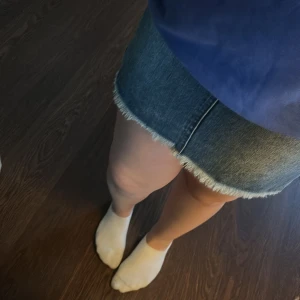 Jeanskjol med fransad kant - Säljer en klassisk blå jeanskjol i kort modell med rå, fransad nederkant. Kjolen har normal passform och dragkedja framtill. Perfekt för dig som gillar en enkel och tidlös stil.