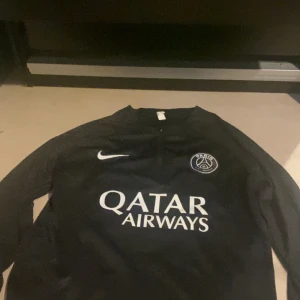 Svart PSG långärmad fotbollströja från Nike - Säljer en svart Paris Saint-Germain fotbollströja från Nike med Qatar Airways som sponsortryck på bröstet. Tröjan har lång ärm och PSG-loggan på vänster sida av bröstet. Storleken är S men passar M
