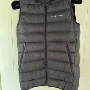 Svart dunväst från Sail Racing - Klassisk svart dunväst från Sail Racing med dragkedja framtill och två praktiska fickor med dragkedja. Perfekt för lager-på-lager och passar till många olika outfits. Junior 176 så likvärdig S senior. Pris går att diskutera.