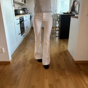 Vita bootcut byxor från Zara - Säljer ett par vita bootcut-byxor från Zara i storlek XS. Byxorna har normal midja och vida ben med pressveck framtill. Snygg passform och klassisk look, perfekta till många olika outfits. Aldrig andvänts, (fick i present därav ingen lapp kvar)