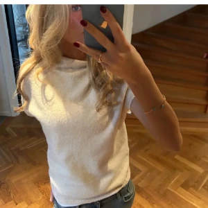 Vit stickad topp från Lindex - Säljer en vit stickad topp från Lindex i storlek S. Toppen har korta ärmar, lös passform och en lite högre krage. Perfekt att styla med jeans eller kjol för en avslappnad look. 
