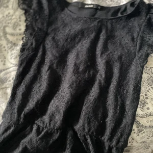 Svart spetsig topp - Supersöt svart topp från Bik Bok i spetsmaterial. Korta ärmar med volangdetaljer och rund halsringning. 🩷