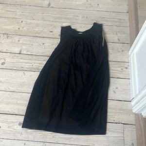 Svart ärmlös klänning - Säljer en svart ärmlös klänning med lös passform och rund halsringning. Klänningen har ett enkelt och stilrent utseende, perfekt för dig som gillar minimalistisk stil. Tunnare material som ger ett fint fall.