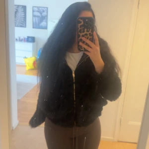 Svart pälsjacka från New Look - Säljer en svart pälsjacka från New Look med glansigt foder och dragkedja framtill. Jackan har lång ärm och en klassisk, lite fluffig look som ger en trendig vibe. Perfekt för dig som vill sticka ut med en snygg och mysig jacka. Lite skadad på insidan men de syns inte