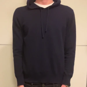 Mörkblå hoodie - Säljer en enkel och stilren mörkblå hoodie med huva och dragsko. Tröjan har långa ärmar och en klassisk passform, perfekt för vardagsbruk. Passar dig som gillar en clean och tidlös look.