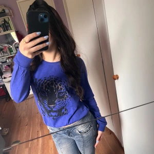 Blå sweatshirt med leopardtryck från Gina Tricot - Säljer en blå sweatshirt från Gina Tricot med ett svart leopardtryck framtill. Tröjan har rund halsringning och långa ärmar. Perfekt för en avslappnad och cool stil.