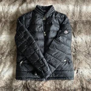 Moncler agay  - Tja, säljer nu min Moncler agay jacka. Fint skick förutom lappen på vänster arm (bild 5), syns ej vid användning. Denna modell är tunnare och utan luva så är därför perfekt för våren och kyliga sommardagar. Men passar även till hösten. Givetvis garanteras äkthet. ÄR ÖPPEN FÖR BUD OCH BYTEN. Om du har fler frågor är det bara att skriva// Hugo Borgström 