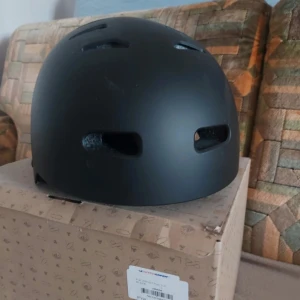 Svart hjälm med matt finish - Säljer en stilren svart hjälm med matt finish och flera ventilationshål. Perfekt för cykling, skateboard eller annan träning. Sitter bekvämt på huvudet och har en enkel, modern design.