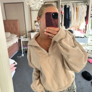 Beige half zip sweatshirt - Beige sweatshirt med half zip och krage. Tröjan har en loose passform och långa ärmar med breda muddar. Perfekt för chill dagar och enkel att matcha med jeans eller mjukisbyxor.