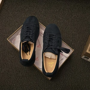 Mörkblå sneakers från Louboutin - Snygga mörkblå sneakers från Louboutin i mocka med klassisk röd sula och broderad logga baktill. Skorna har rund tå, snörning och diskreta detaljer som ger en lyxig känsla. Perfekta för dig som vill sticka ut med stil.