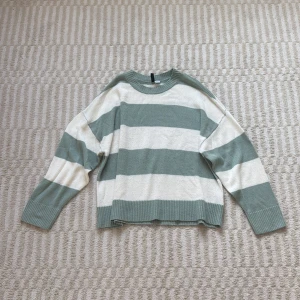 Randig stickad tröja från Divided - Supermysig stickad tröja från Divided i grönt/blått och vitt med breda ränder. Tröjan har rund halsringning, ribbade muddar och avslappnad passform. Perfekt för lager-på-lager och chill dagar.