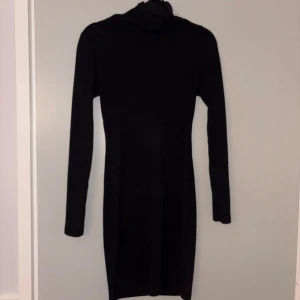 Svart ribbad poloklänning - Säljer en svart, tight ribbad klänning med polokrage och långa ärmar. Klänningen är kort och har en stilren, minimalistisk look som passar perfekt till sneakers eller boots. Superenkel att styla och ett måste i garderoben!