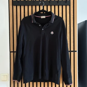 Mörk blå långärmad pikétröja Moncler - Använd och väl omhändertagen. Har ett väldigt litet hål som är omsytt vid armbågen som ej syns när du har på dig den. Storlek Small