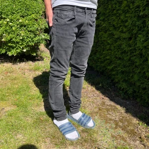 Replay Anbass Hyperflex svart gråa jeans - Svart gråa Replay Anbass Hyperflex jeans i slim fit med klassisk femficksdesign. Jeansen har en snygg tvättad look, normal midja och smal passform hela vägen ner. Stretchigt material som gör dem riktigt bekväma att bära. Perfekta för dig som gillar stilrena och moderna jeans.