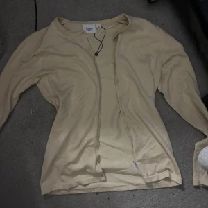 Beige kofta från Saint Tropez XS - Snygg beige kofta från Saint Tropez i storlek XS. Koftan har långa ärmar, knappar framtill och är tillverkad i ett tunt, mjukt material som känns skönt mot huden. Perfekt att slänga över en topp för en chill och stilren look.