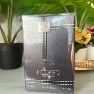 Hooked Pour Homme Rue Broca parfym - Maskulin parfym med aromatiska och söta toner av karamell, amber, vanilj och citrus. Flaskan är mörkgrön med svart rosett och rund kork, och kommer i en elegant svart kartong med vita sömmar. 100 ml eau de parfum.inspired by Scandal Pour Homme Edt 2021