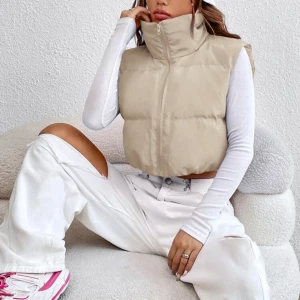 Beige eller svart croppad dunväst 250kr för två - Säljer den här västen med två olika färger ( svart och beige) med hög krage och dragkedja framtill. Västen är quiltad och finns i både beige och svart. Perfekt att slänga över en långärmad tröja för en chill och trendig look. Passformen är loose och västen är lätt vadderad för extra värme.