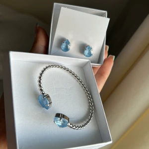 Caroline Svedbom sky ignite - Säljer ett snyggt smyckeset från Caroline Svedbom med ett silverfärgat armband och matchande örhängen till. Både armbandet och örhängena har droppformade ljusblå stenar som är så fina! 🩵Örhängena är oanvända och armbandet användes en gång 