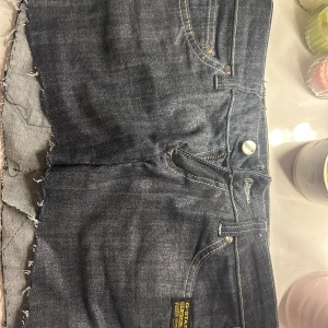 Jeanskjol från G-Star RAW med dragkedjor - Cool kort jeanskjol från G-Star RAW i mörkblå denim med råa kanter och stora broderade loggor på baksidan. Kjolen har dragkedjor på bakfickorna och klassiska jeansdetaljer som knapp och bälteshällor. Perfekt för en edgy streetstyle-look. (sydd själv från ett par skinnyjeans)