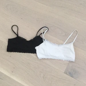 2  toppar från H&M - Två barntoppar från H&M, en svart och en vit. Båda har tunna axelband och spetskant overs och underst. Perfekta att ha under en t-shirt eller ett linne. Mjukt material som känns skönt mot huden.
