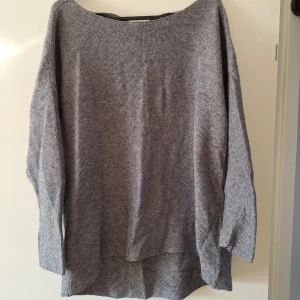 Grå stickad tröja med knyt i ryggen - Mysig grå stickad tröja från Mohito med v-ringning och snygg knytning i ryggen. Tröjan har 3/4 ärm och en loose passform som ger en avslappnad vibe.