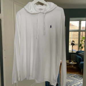 Ralph lauren hoodie - Tunn och vit Ralph lauren hoodie med blå brodering i grymt skick! Perfekt plagg nu under sommaren.🕶️ Tröjan har ett hål som fixats men som inte märks vid använding! Pris kan diskuteras:)