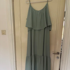 Ljusblå långklänning med volang - Superfin ljusblå långklänning med tunna axelband och volang upptill. Klänningen har en luftig och flowy passform, perfekt för varma dagar. Materialet känns lätt och svalt mot huden. Enkel men ändå elegant stil som sticker ut. Använd bara fåtalet gånger. XL