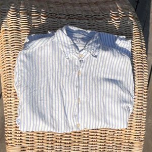 Randig skjorta från Zara i linne - Säljer en fräsch skjorta från Zara i ljusblått och vitt randigt mönster. Skjortan är tillverkad i svalt linne, har klassisk krage och knäppning framtill. Perfekt för varma dagar och enkel att styla till jeans eller shorts.