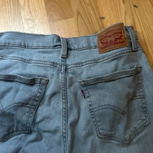 Levi's 724 High Rise Straight jeans - Snygga ljusblå Levi's 724 High Rise Straight jeans med klassisk femficksdesign och raka ben. Hög midja och ikonisk läderpatch baktill. Perfekta för en avslappnad och trendig look.